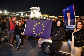 Participants display an election campaign poster of Hungary's prime minister-elect, Peter Magyar and a flag of the European Union during a spontaneous gathering to celebrate the victory of the conservative Tisza party near the Szechenyi Chain Bridge in Budapest